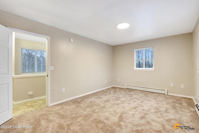 spare room featuring plenty of natural light, light colored carpet, and a baseboard heating unit