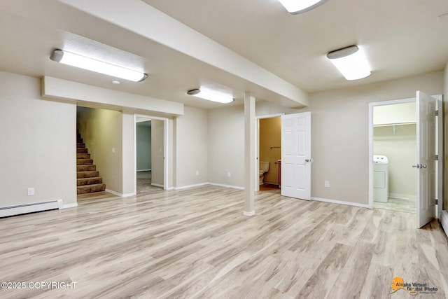 basement featuring baseboard heating, washer / clothes dryer, and light wood-type flooring