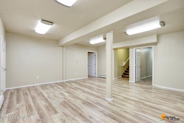 basement featuring light hardwood / wood-style floors and a baseboard heating unit