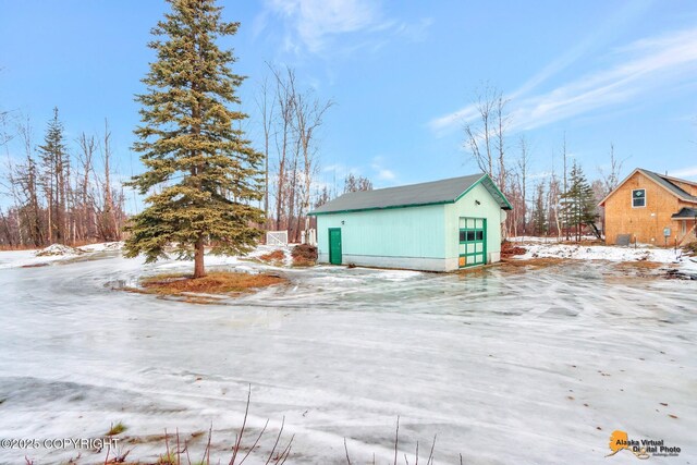 view of snowy exterior with a garage and an outbuilding