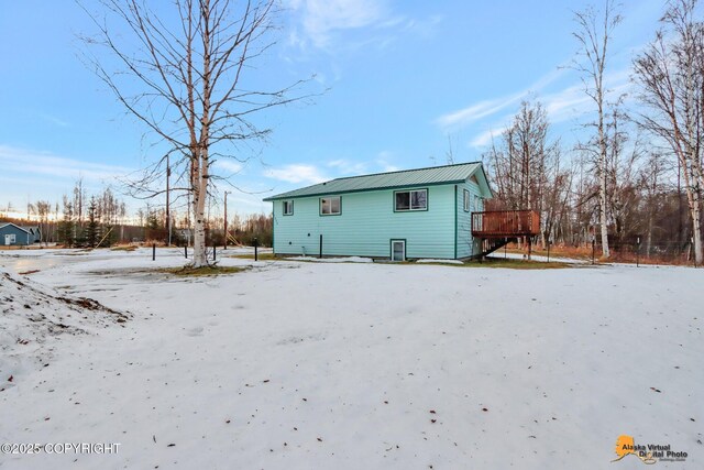 snow covered back of property with a deck