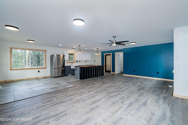 unfurnished living room with ceiling fan, sink, and light hardwood / wood-style flooring