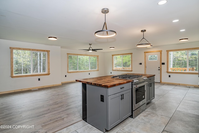 kitchen with wooden counters, ceiling fan, high end stainless steel range, gray cabinets, and hanging light fixtures