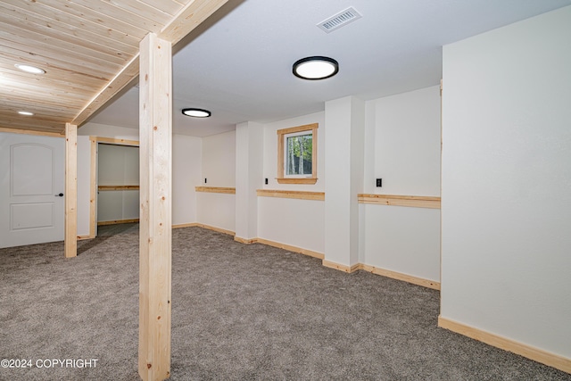 basement featuring dark colored carpet and wood ceiling