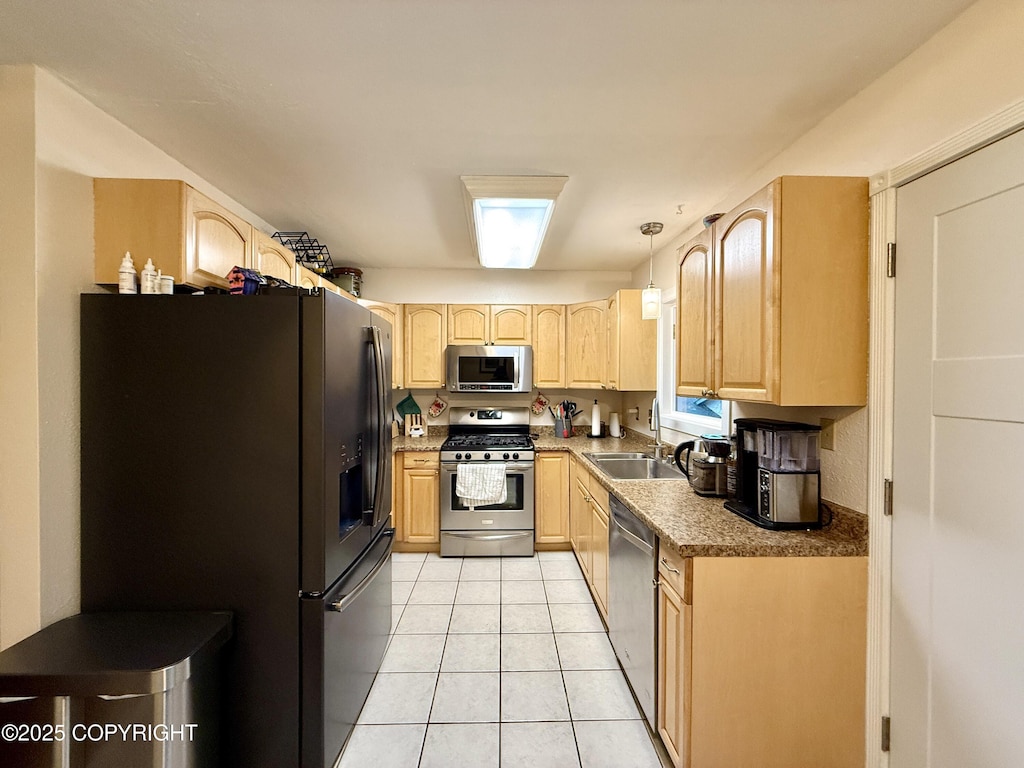 kitchen featuring sink, light tile patterned flooring, hanging light fixtures, appliances with stainless steel finishes, and light brown cabinetry