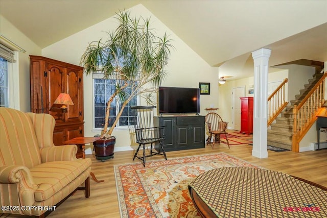 living room featuring lofted ceiling, light hardwood / wood-style flooring, and ornate columns