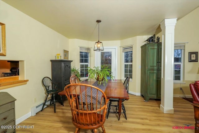 dining area with light hardwood / wood-style floors, a baseboard heating unit, and ornate columns