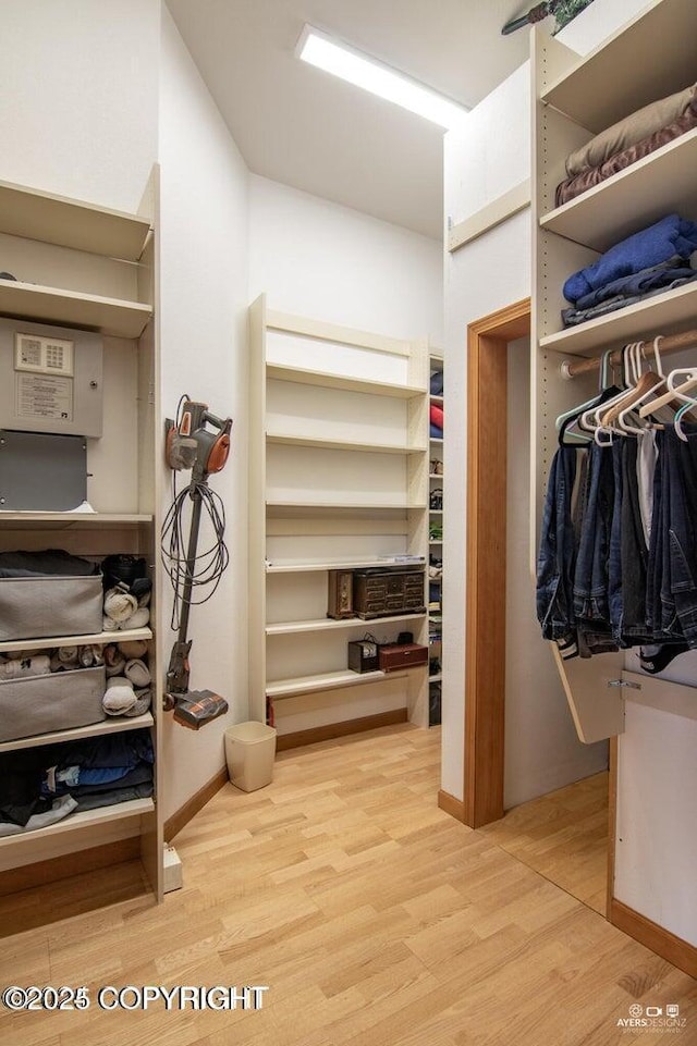 walk in closet with light hardwood / wood-style flooring