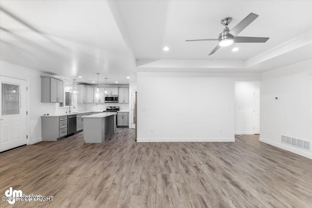 unfurnished living room featuring hardwood / wood-style flooring, ceiling fan, and sink