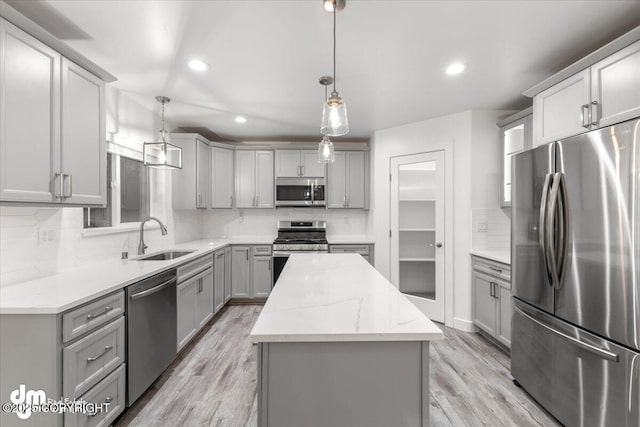 kitchen featuring decorative light fixtures, a kitchen island, sink, and stainless steel appliances