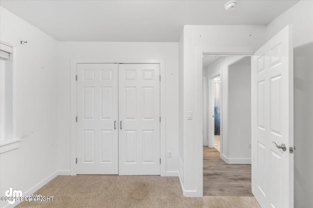 unfurnished bedroom featuring light carpet and a closet