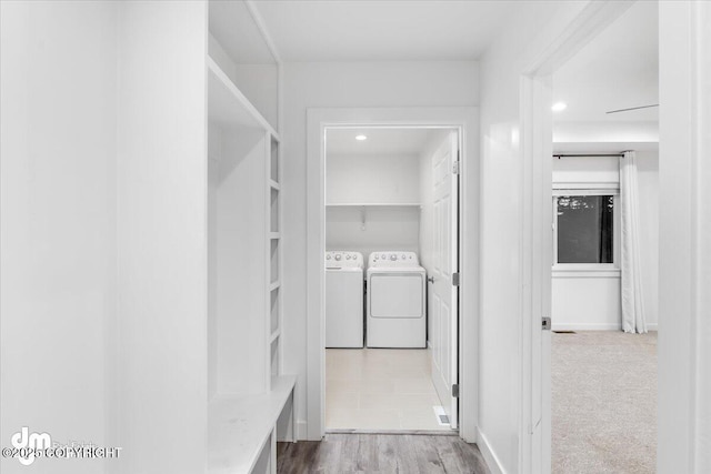 hall featuring washing machine and clothes dryer and light colored carpet