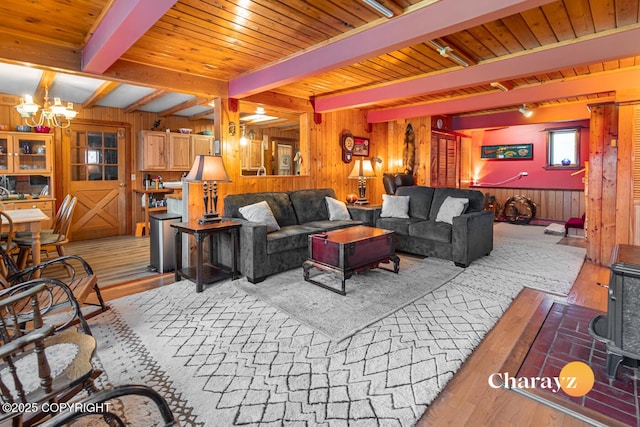 living room with beam ceiling, wood walls, a chandelier, and wooden ceiling