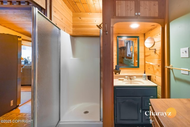 bathroom featuring walk in shower, vanity, wood ceiling, and wood walls