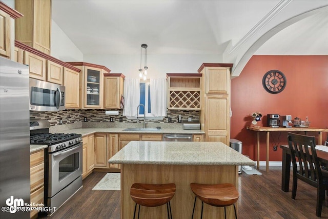 kitchen featuring sink, a center island, hanging light fixtures, stainless steel appliances, and backsplash