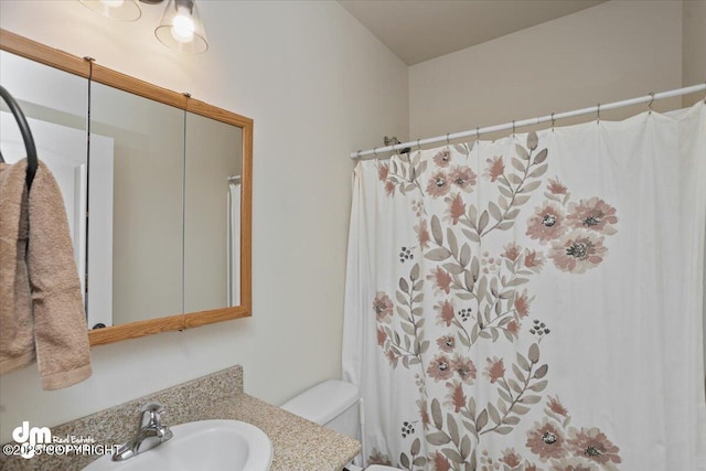 bathroom with walk in shower, vanity, and toilet