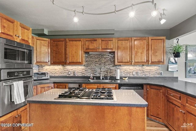 kitchen with a center island, backsplash, sink, light hardwood / wood-style flooring, and stainless steel appliances