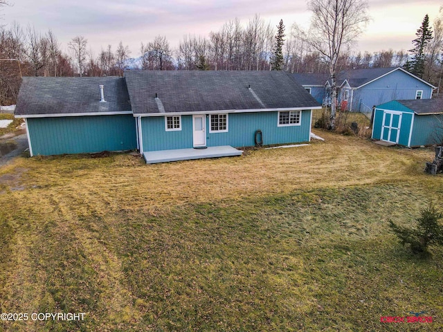 back house at dusk with a lawn, a wooden deck, and a storage shed