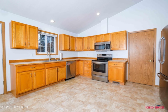 kitchen featuring stainless steel appliances, vaulted ceiling, and sink