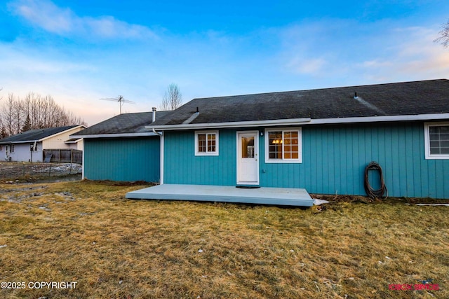 back house at dusk featuring a lawn and a wooden deck