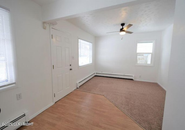 entryway with ceiling fan, a healthy amount of sunlight, baseboard heating, and light carpet