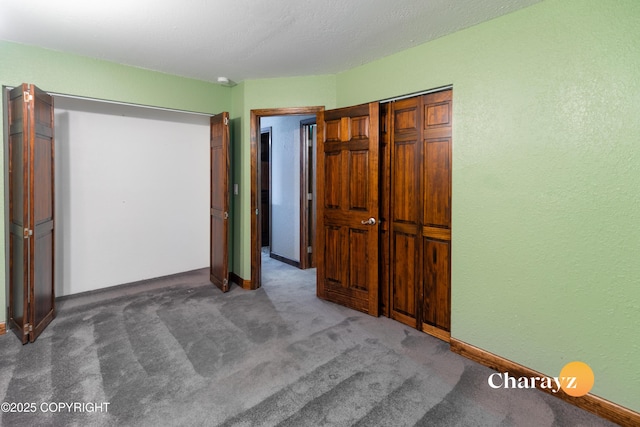 unfurnished bedroom featuring dark carpet and a closet