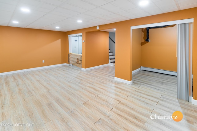 basement featuring light hardwood / wood-style flooring and a baseboard heating unit