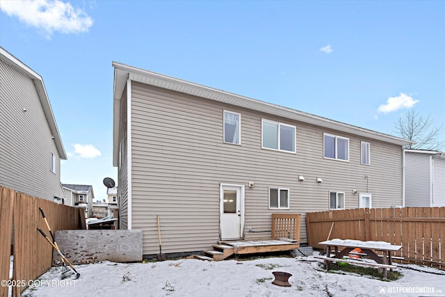 snow covered rear of property with a wooden deck