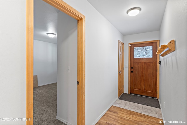 doorway to outside featuring baseboards and carpet flooring