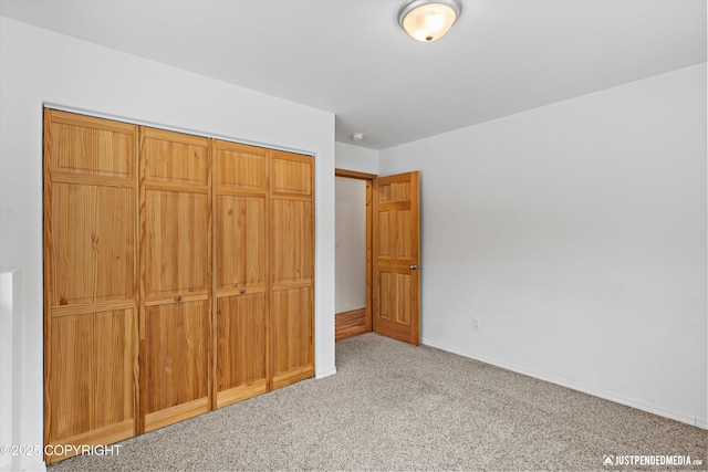 unfurnished bedroom featuring a closet, baseboards, and carpet