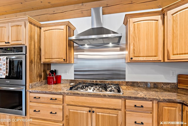 kitchen with stainless steel appliances, light brown cabinetry, and wall chimney range hood