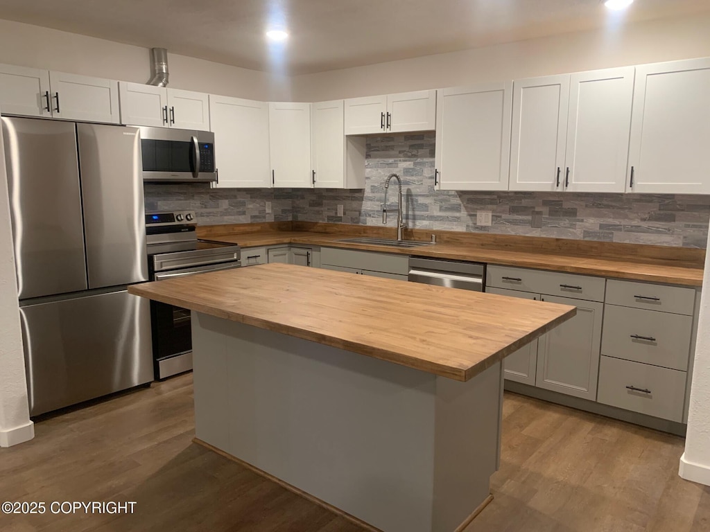 kitchen featuring a center island, wooden counters, sink, white cabinetry, and stainless steel appliances