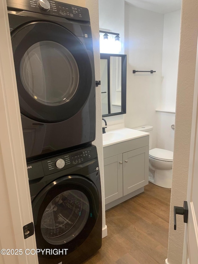 laundry room featuring stacked washer / dryer, sink, and light hardwood / wood-style floors