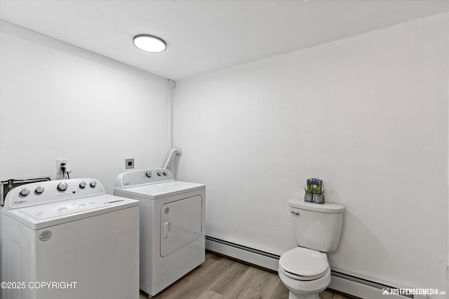 laundry room with washer and dryer, baseboard heating, and light wood-type flooring