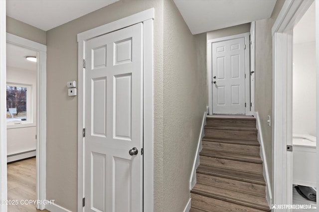 staircase featuring baseboard heating and hardwood / wood-style flooring