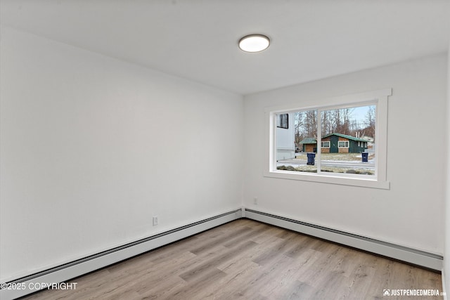 unfurnished room with baseboard heating and light wood-type flooring