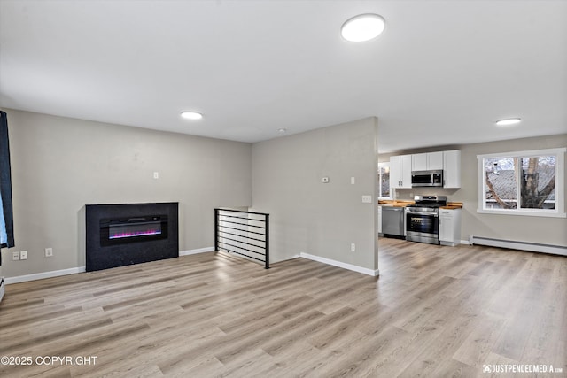 unfurnished living room with baseboard heating and light hardwood / wood-style flooring