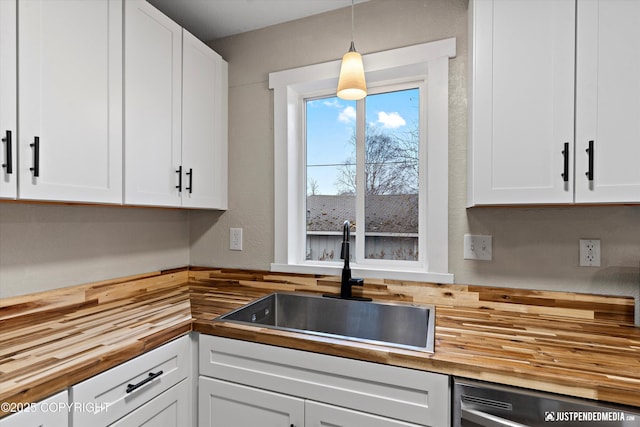 kitchen featuring wood counters, decorative light fixtures, dishwasher, white cabinetry, and sink