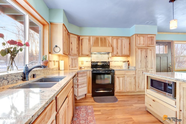 kitchen featuring sink, decorative light fixtures, light brown cabinets, premium range hood, and appliances with stainless steel finishes