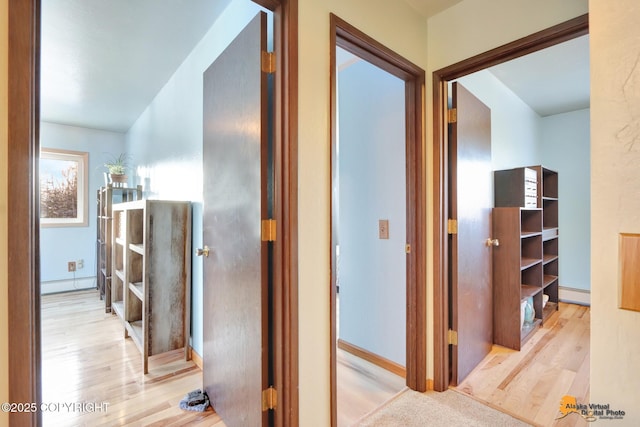 corridor with baseboard heating and light hardwood / wood-style floors