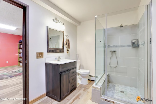 bathroom featuring toilet, wood-type flooring, an enclosed shower, vanity, and baseboard heating