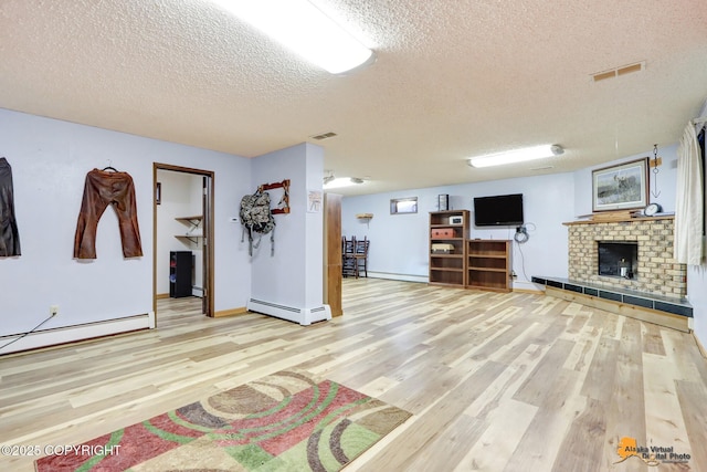 unfurnished living room with a fireplace, a textured ceiling, a baseboard radiator, and light hardwood / wood-style flooring