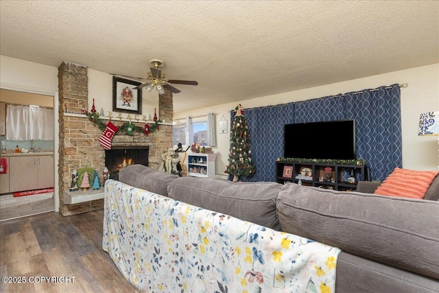 living room featuring a fireplace, dark hardwood / wood-style floors, a textured ceiling, and ceiling fan