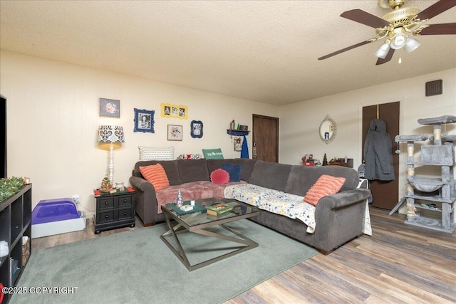 living room with ceiling fan, a textured ceiling, and hardwood / wood-style flooring