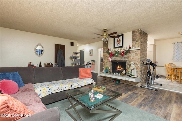 living room featuring a fireplace, a textured ceiling, hardwood / wood-style flooring, and ceiling fan