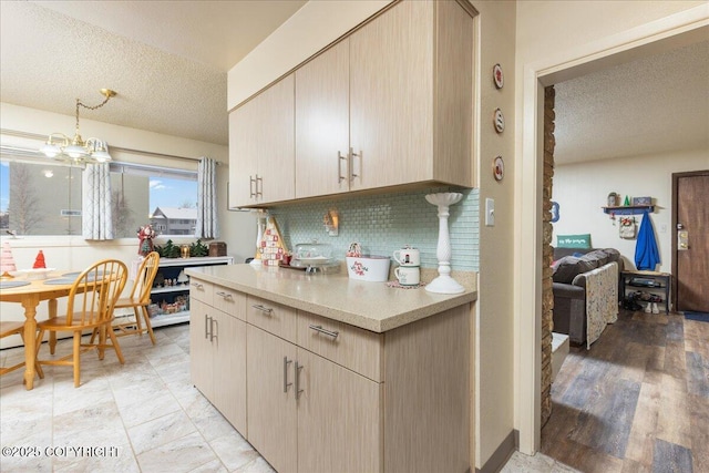 kitchen with hanging light fixtures, tasteful backsplash, a chandelier, a textured ceiling, and light brown cabinetry