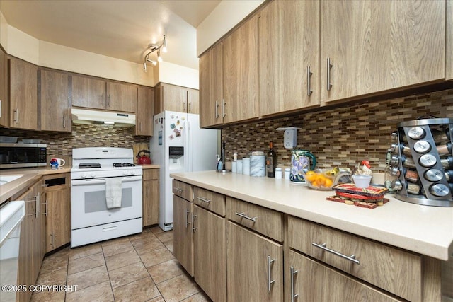 kitchen with backsplash, light tile patterned floors, and white appliances