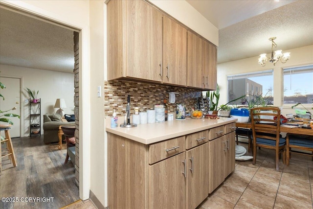 kitchen with a textured ceiling, backsplash, hanging light fixtures, and a chandelier