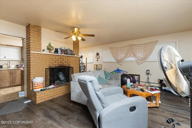 living room with ceiling fan, a fireplace, sink, and hardwood / wood-style flooring