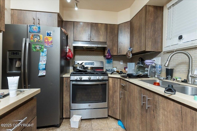 kitchen with backsplash, sink, appliances with stainless steel finishes, dark brown cabinets, and light tile patterned flooring